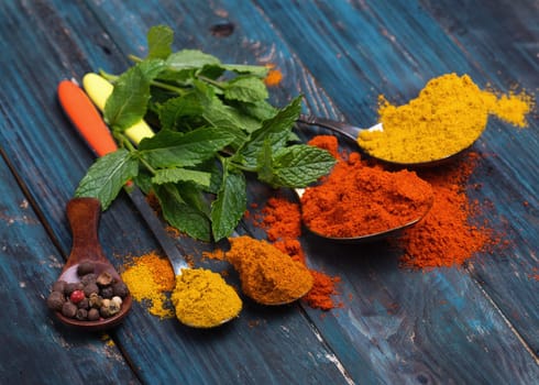 Colorful spices in different wooden spoons on wooden background