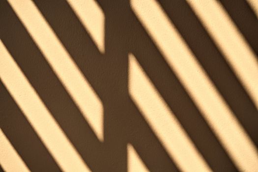 Abstract sunlight shines through the wooden channel against the cement wall.