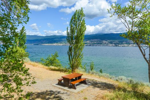Picnic table and benches on shore of Okanagan lake