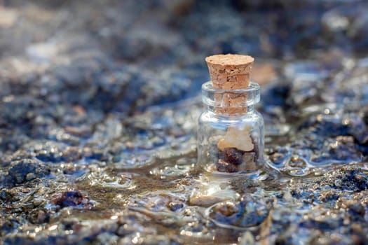 A small decorative jar with stones inside is in the stream. Jar with a cork.