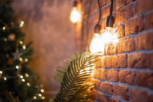 A brick wall with a burning light bulb that creates coziness and New Year's mood. Garland
