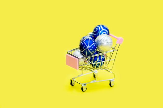 Blue Christmas balls are stacked in a small shopping cart. Christmas shopping