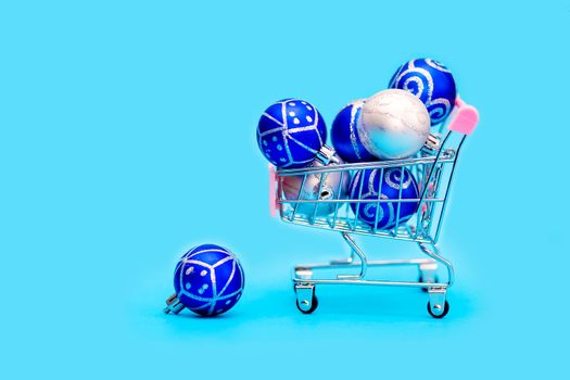 Blue Christmas balls are stacked in a small shopping cart. Christmas shopping