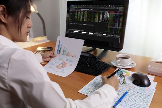 Business woman working in office with computer holding chart report paper and looking. business people working at home with paper and PC screen. Business and finance ,work at home concept