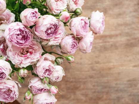 Bouquet of lilac colored roses upon wooden background. Top view, flat lay. Still life banner with copy space.