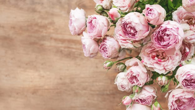 Bouquet of lilac colored roses upon wooden background. Top view, flat lay. Still life banner with copy space.