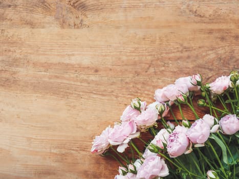 Bouquet of lilac colored roses on wooden background. Top view, flat lay. Still life banner with copy space.