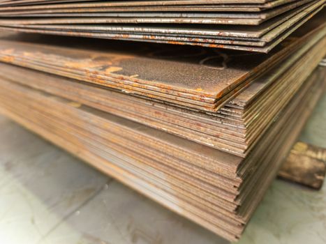 large thin rusted sheet metal stack edge - closeup with selective focus and blur.