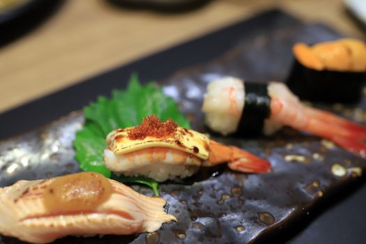 Shrimp sushi topped with grilled cheese and topped with orange roe On a traditional Japanese plate in a Japanese restaurant. Selective focus.