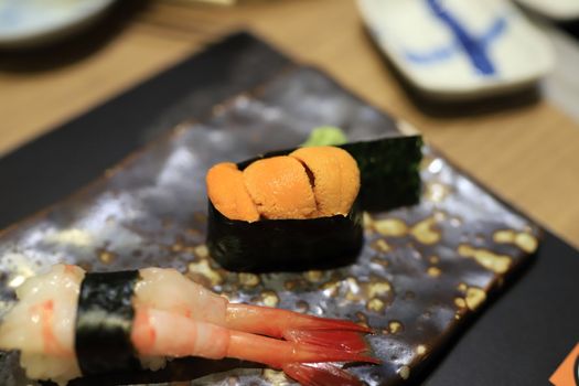 Sea urchin sushi wrapped in seaweed on a traditional Japanese dish in a Japanese restaurant. Selective focus.