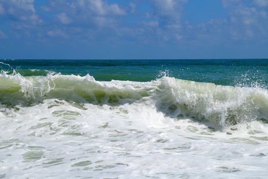 big white waves hitting the sea shore on the sunny day