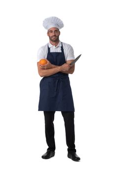 Male cook in apron and hat holding orange and knife isolated on white background, full length portrait