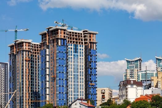 The construction of modern residential buildings made of concrete with a glass facade comes close to and rises above the country houses of low-rise buildings, a copy of the space.