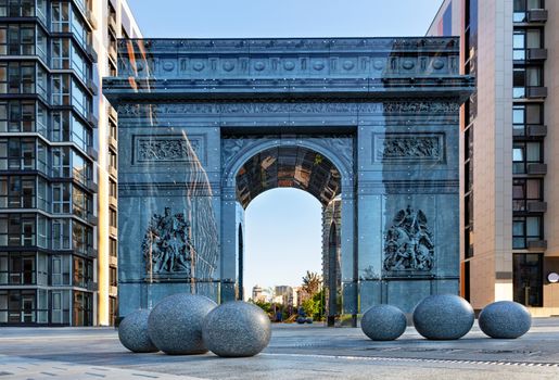 Kyiv, Ukraine, a modern stylized triumphal arch reminiscent of the famous Arc de Triomphe in Paris, located in the French quarter of Kyiv. Stone granite balls in the foreground, drawing on the glass facade.