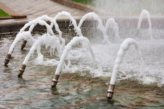 In the city fountain, metal cannons create a beautiful water carousel of foaming jets of water that powerfully burst to the surface.