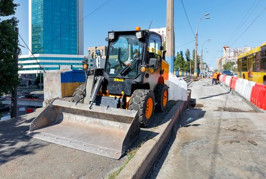 A light construction bulldozer during the repair of an asphalt road on a city street at noon.