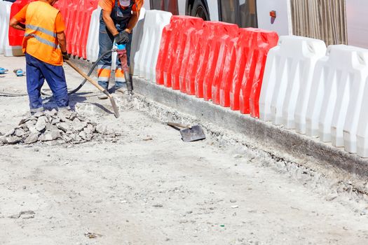 Workers remove old asphalt concrete with a pneumatic jackhammer during road construction, image with copy space.