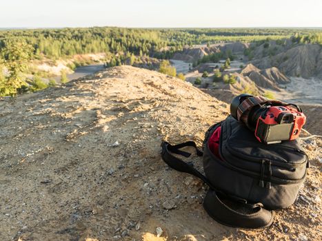 professional camera and photo backpack on top of the hill at summer daytime.