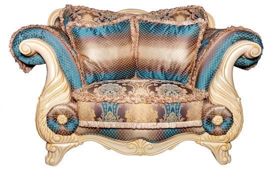A beautiful soft sofa for two, upholstered with expensive brocade textile upholstery in turquoise and gold tones, with soft pillows, with curved carved legs, photographed from the front, isolated on a white background.