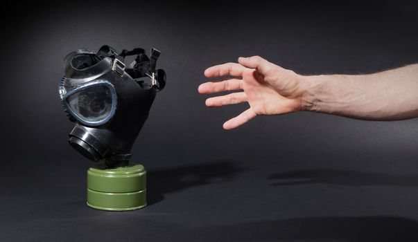 Man in room, trying to reach for vintage gasmask - Isolated on black - Green filter