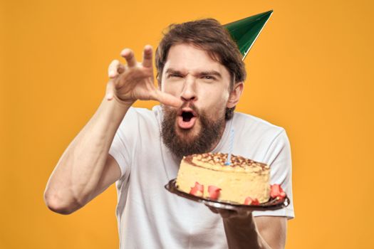 birthday boy in a cap with cake fun yellow background party. High quality photo