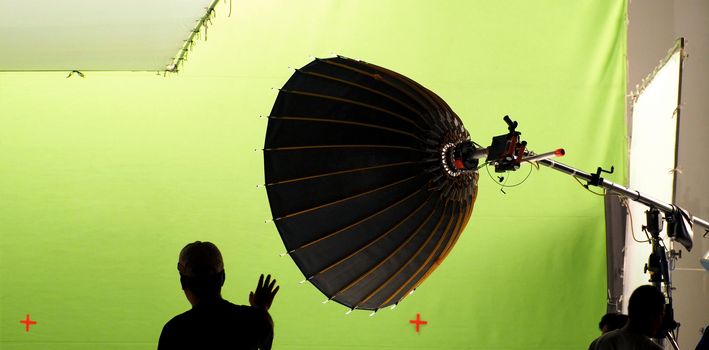 Big studio light equipments and man setting for shooting movie video or photo film and green screen background.