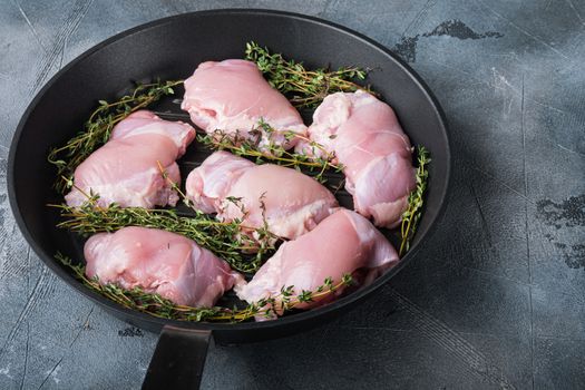 Chicken thighs with thime on grill pan on grey background.