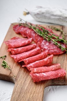 Salchichon whole and sliced cuts, spanish sausage on white textured background.