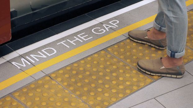 Text sign on floor between train and platform "Mind the gap" with white color and high angle view. 