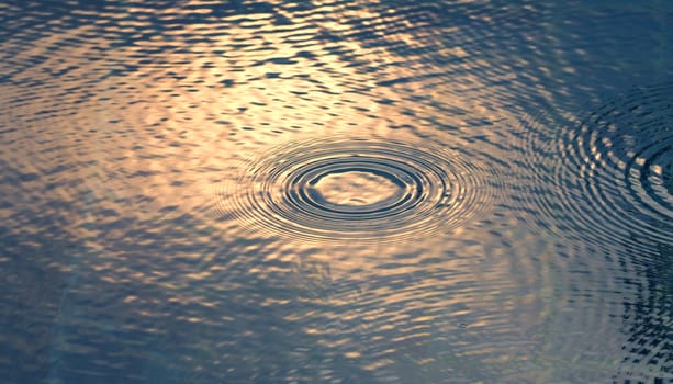 Rain drop falling on pool and have ripple shape and sun light reflection on surface for abstract background. 