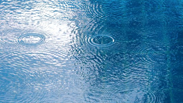 Rain drop falling on pool and have ripple shape and sun light reflection on surface for abstract background. 