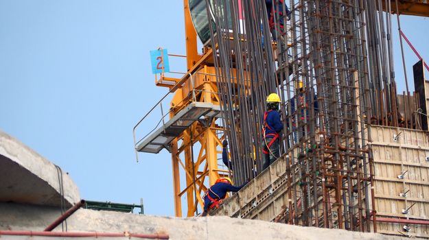 Construction site and worker that working on high building and concrete steel material.