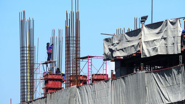 Construction site and worker that working on high building and concrete steel material.