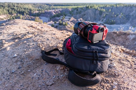 professional camera and photo backpack on top of the hill at summer daytime.
