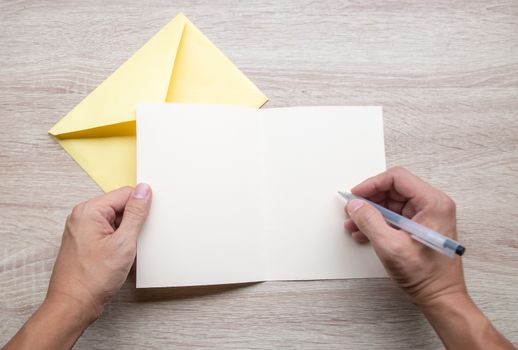 Male hands writing Empty cards on wooden table.