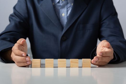 Hands of entrepreneur business man holding wooden blocks placing to a structure, Concept of teamwork, strategy, professional manager work for executive investor to corporate wealth of fundamental.