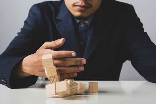 Hands of entrepreneur business man holding wooden blocks placing to a structure, Concept of teamwork, strategy, professional manager work for executive investor to corporate wealth of fundamental.