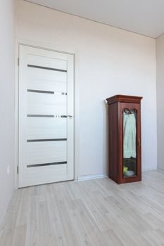 Fragment of an empty room interior with a small cabinet and a door