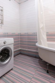 View of an empty corner in the bathroom, with a washing machine and a bathroom on the sides