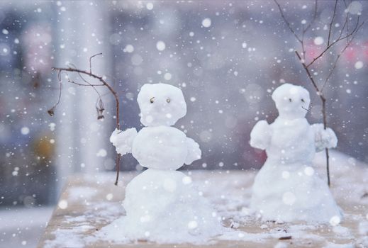 Two little cute snowmen with branches instead of hands Christmas background New Year mood.