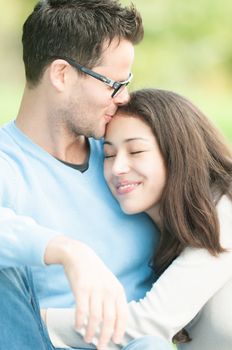 Portrait of young sweet couple spending time outdoor together. Woman leaning on man's shoulder with her eyes closed. Quiet and peaceful atmosphere. Romantic relationships. Family and love.