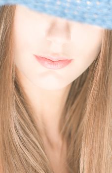 Portrait of pretty girl with her eyes under blue crocheted hat isolated on white background. Half hidden beautiful face. Woman beauty and mystery. Shy and modest.