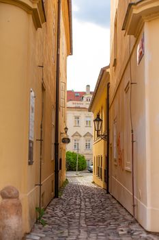 The architecture of the strago city of Prague. Old european streets, yellow low buildings and stone paving stones.