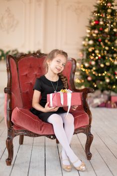 A little girl opens a Christmas present from Santa. Christmas tale. Happy childhood.