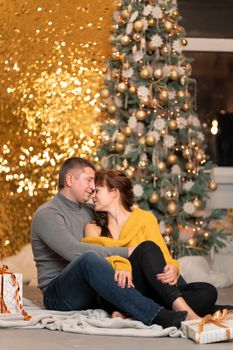 A beautiful cheerful couple greets the Christmas holidays in a cozy home atmosphere.