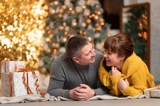 A beautiful cheerful couple greets the Christmas holidays in a cozy home atmosphere.