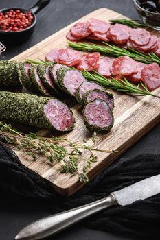 Spanish fuet salami sausage slices on black textured background.