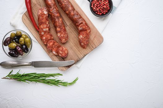Traditional chorizo cuts with spices and ingredients on white textured background with space for text.