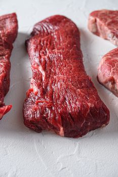 Raw tri-tip triangle roast or bottom sirloin steak cut organic meat cut side view close up over white concrete background vertical selective focus.