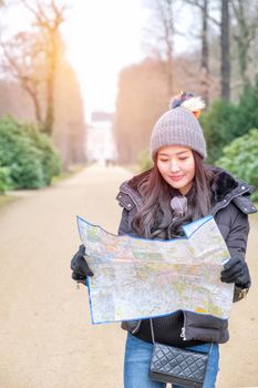 Young female tourist with map looking for a way to Sans Souci palace in Potsdam, Berlin, Germany, Europe.